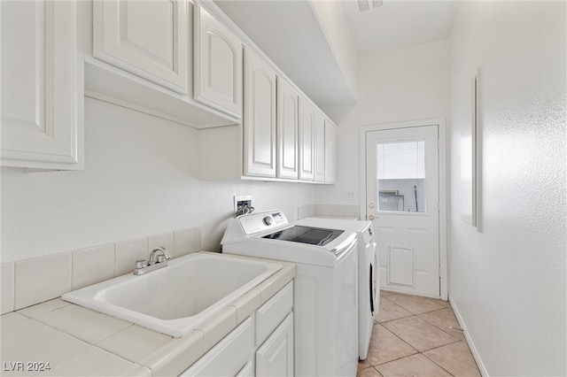 laundry area featuring cabinets, light tile patterned floors, separate washer and dryer, and sink