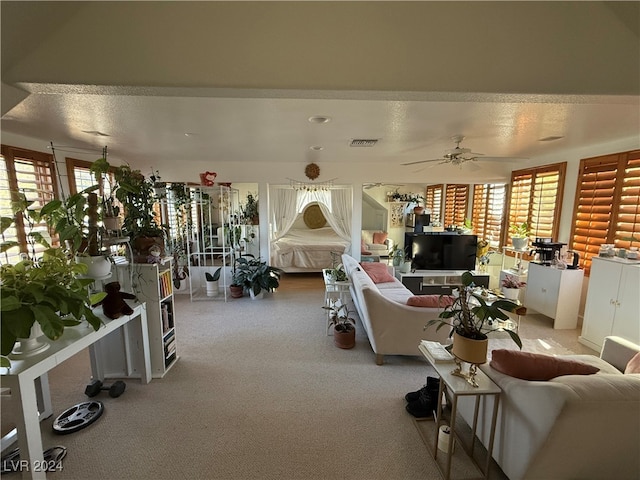 living room with a textured ceiling, carpet flooring, and ceiling fan