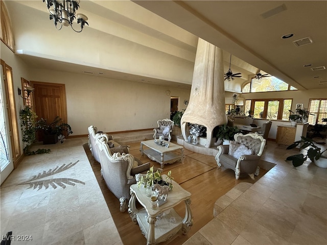 living room featuring ornate columns, lofted ceiling, and ceiling fan with notable chandelier