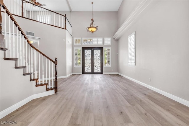 entrance foyer featuring french doors, light hardwood / wood-style floors, and a high ceiling