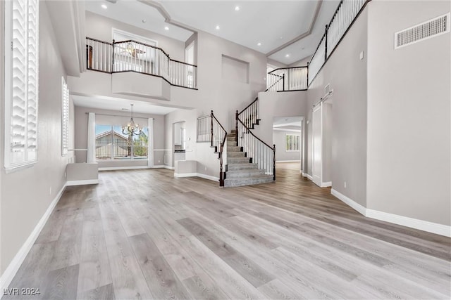 entryway with light wood-type flooring, a high ceiling, and a chandelier