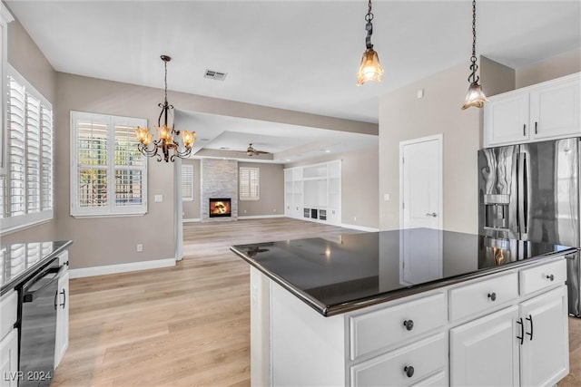 kitchen featuring white cabinets, decorative light fixtures, a kitchen island, and a fireplace