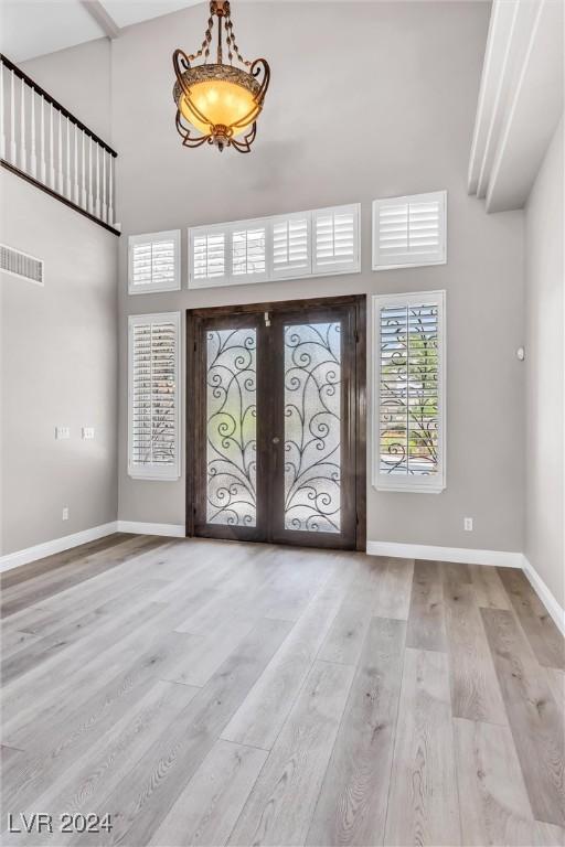 foyer featuring light wood-type flooring, a high ceiling, and french doors