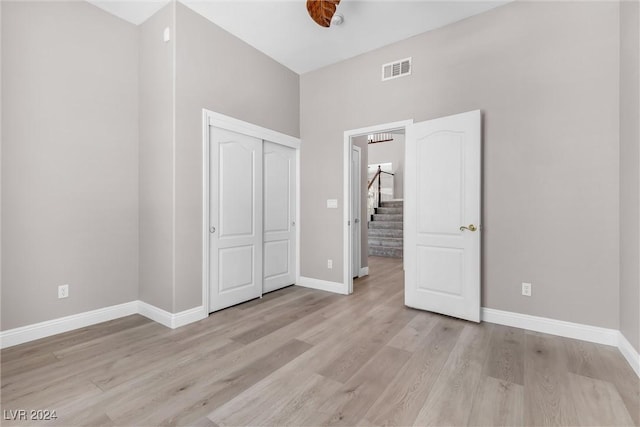 unfurnished bedroom featuring ceiling fan, light wood-type flooring, and a closet