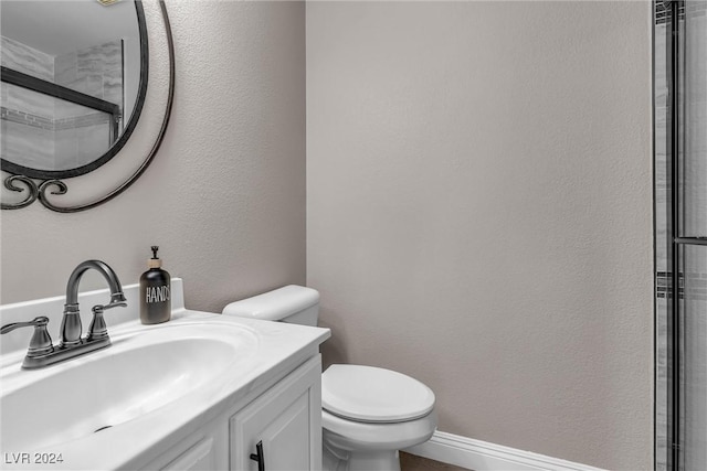 bathroom with vanity, toilet, and a shower with door