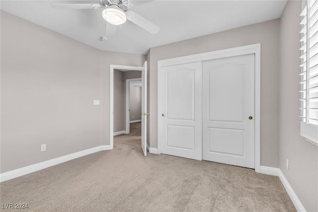 unfurnished bedroom with ceiling fan, a closet, and light carpet