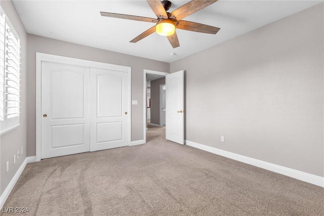 unfurnished bedroom featuring ceiling fan, a closet, and light colored carpet