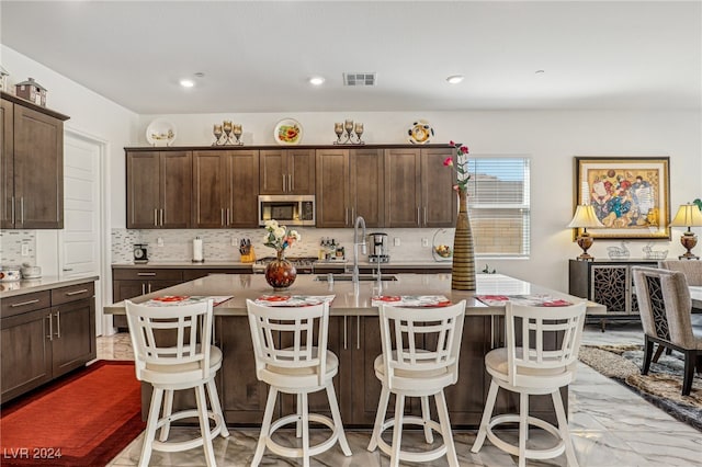 kitchen featuring a breakfast bar area, an island with sink, stainless steel appliances, and sink