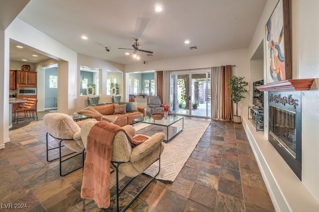 living room with a fireplace and ceiling fan