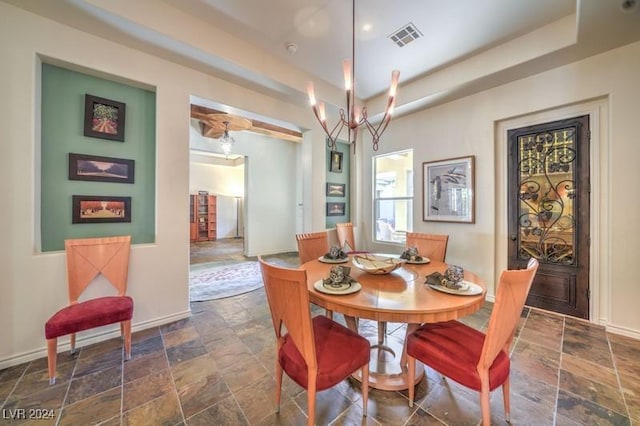 dining area with a raised ceiling and a notable chandelier