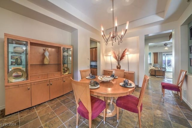 dining room featuring ceiling fan with notable chandelier and a raised ceiling