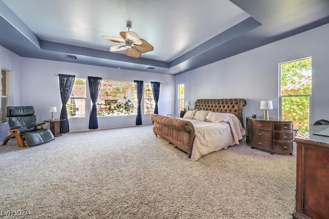 carpeted bedroom featuring a tray ceiling and ceiling fan