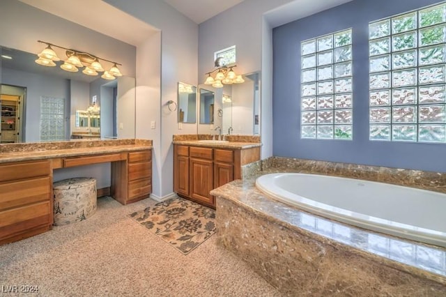 bathroom featuring vanity, a healthy amount of sunlight, and a relaxing tiled tub