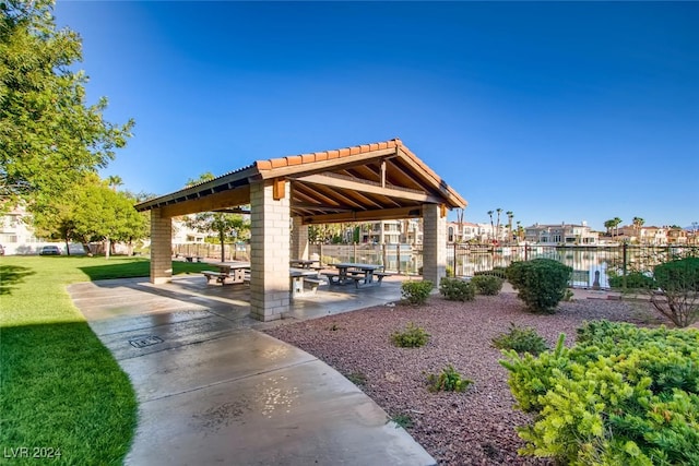 surrounding community with a gazebo, a yard, a water view, and a patio area