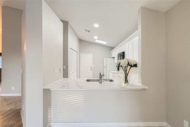 bathroom with hardwood / wood-style floors, lofted ceiling with skylight, and sink