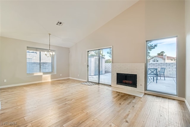 unfurnished living room featuring light hardwood / wood-style floors, a brick fireplace, and plenty of natural light