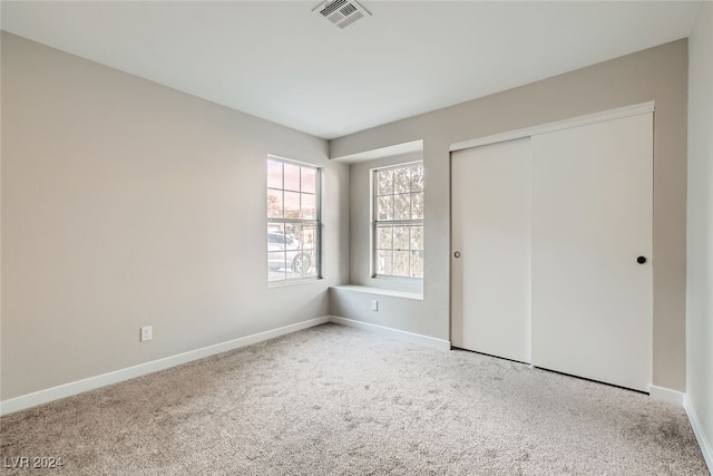 unfurnished bedroom with light colored carpet and a closet