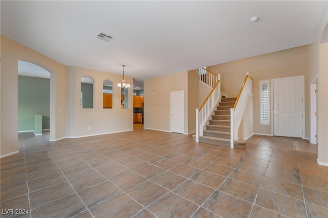 unfurnished living room with light tile patterned floors and an inviting chandelier