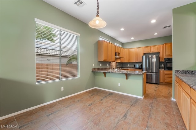 kitchen featuring a kitchen bar, kitchen peninsula, decorative light fixtures, black oven, and stainless steel refrigerator