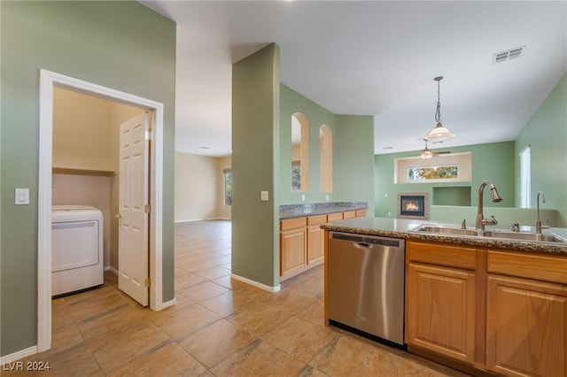 kitchen with sink, stainless steel dishwasher, pendant lighting, washer / dryer, and light tile patterned floors