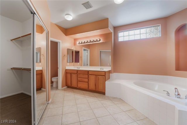 bathroom featuring tile patterned floors, vanity, a relaxing tiled tub, and toilet