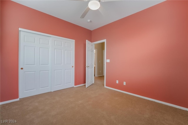 unfurnished bedroom with light carpet, a closet, and ceiling fan