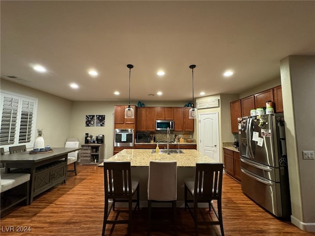 kitchen with dark wood-type flooring, pendant lighting, stainless steel appliances, and sink