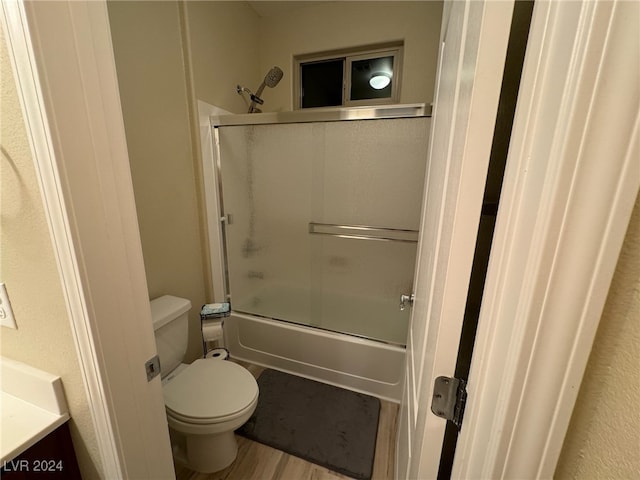 full bathroom featuring wood-type flooring, enclosed tub / shower combo, vanity, and toilet