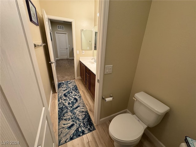 bathroom with wood-type flooring, vanity, and toilet