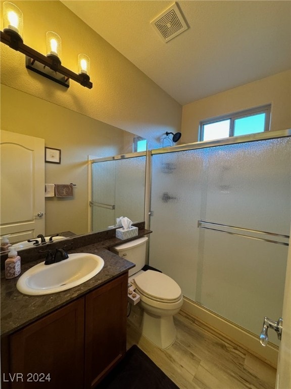 bathroom featuring hardwood / wood-style floors, walk in shower, vanity, and toilet