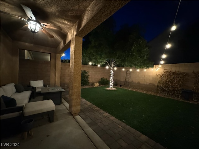 patio at twilight with ceiling fan and a yard