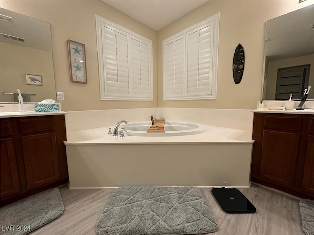 bathroom featuring vanity, hardwood / wood-style floors, and a bath