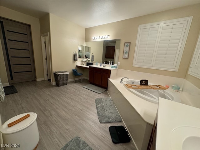 bathroom featuring vanity, toilet, hardwood / wood-style floors, and a bath