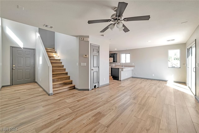 unfurnished living room with light hardwood / wood-style floors, plenty of natural light, ceiling fan, and sink