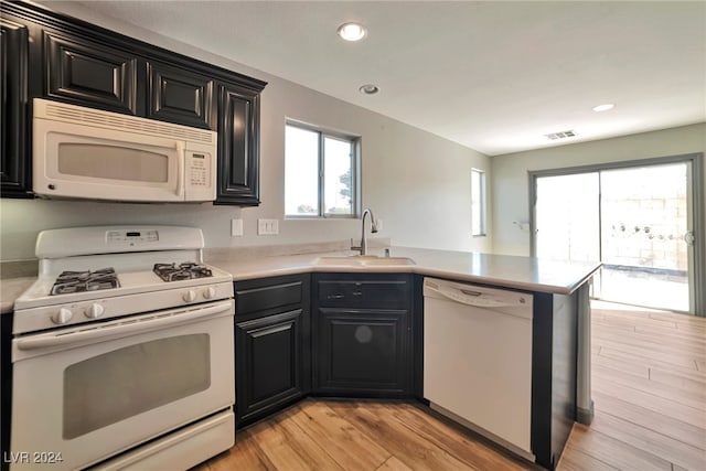 kitchen with kitchen peninsula, white appliances, light hardwood / wood-style floors, and sink