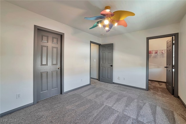 unfurnished bedroom featuring ceiling fan, a closet, light carpet, and a spacious closet