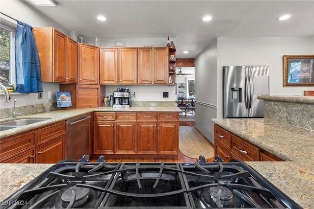 kitchen featuring light stone counters, sink, light wood-type flooring, and stainless steel appliances