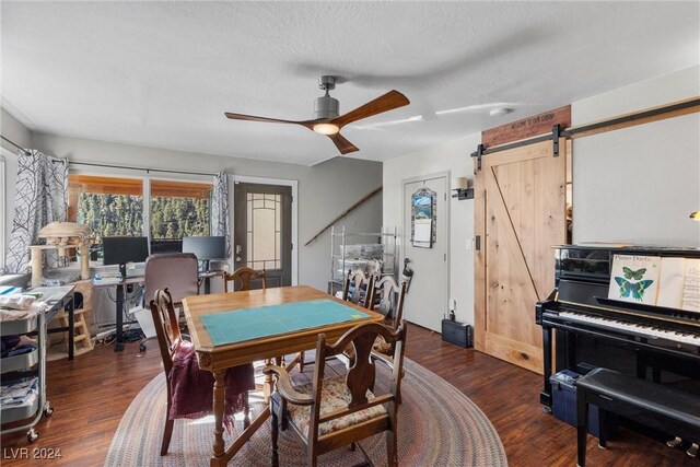 dining space with dark hardwood / wood-style flooring, a barn door, a textured ceiling, and ceiling fan