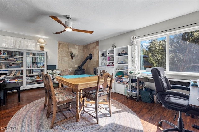 dining area with a wood stove, ceiling fan, dark hardwood / wood-style flooring, and a textured ceiling