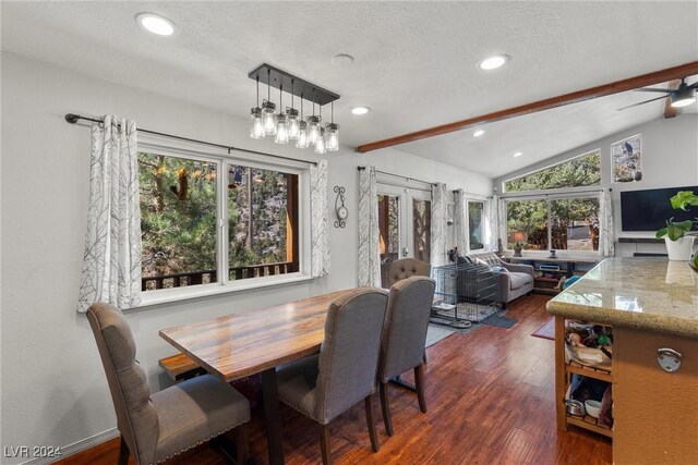 dining space with vaulted ceiling with beams, ceiling fan with notable chandelier, dark hardwood / wood-style floors, and a wealth of natural light