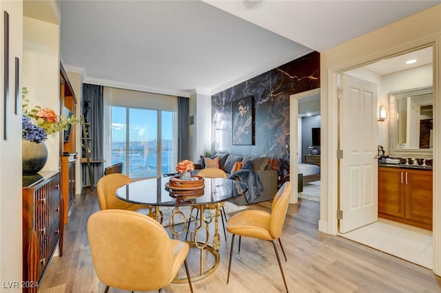 dining room featuring ornamental molding, a water view, light hardwood / wood-style floors, and sink