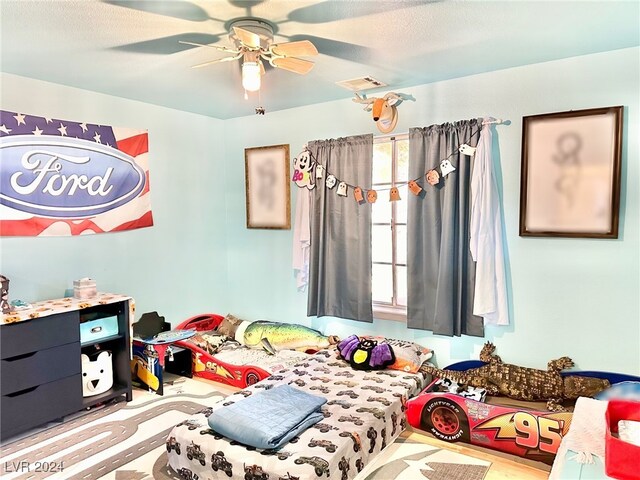 bedroom with light wood-type flooring, ceiling fan, and a textured ceiling