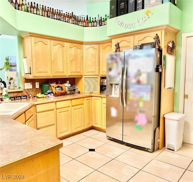 kitchen with light tile patterned floors, light brown cabinets, stainless steel fridge with ice dispenser, and sink