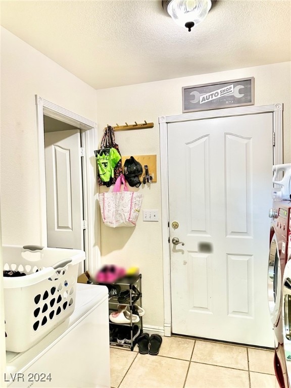 clothes washing area featuring light tile patterned flooring, washer and dryer, and a textured ceiling