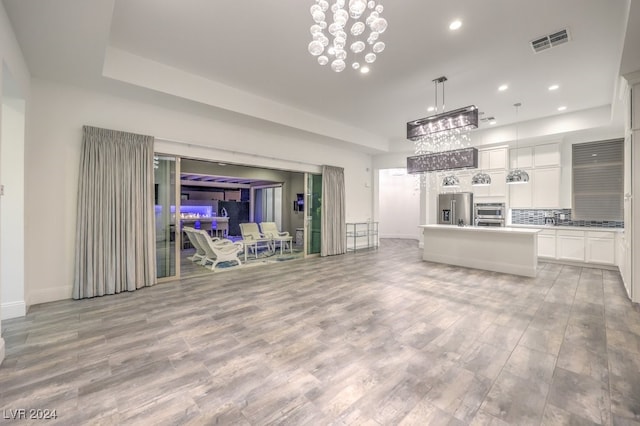 unfurnished living room with light wood-type flooring and a chandelier