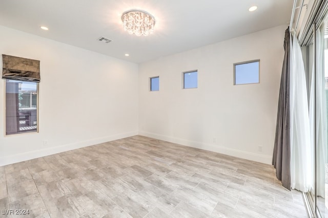 spare room with a notable chandelier and light hardwood / wood-style floors