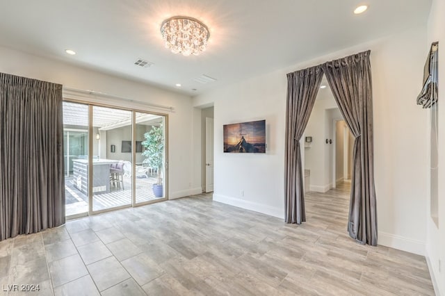 empty room featuring an inviting chandelier and light hardwood / wood-style flooring