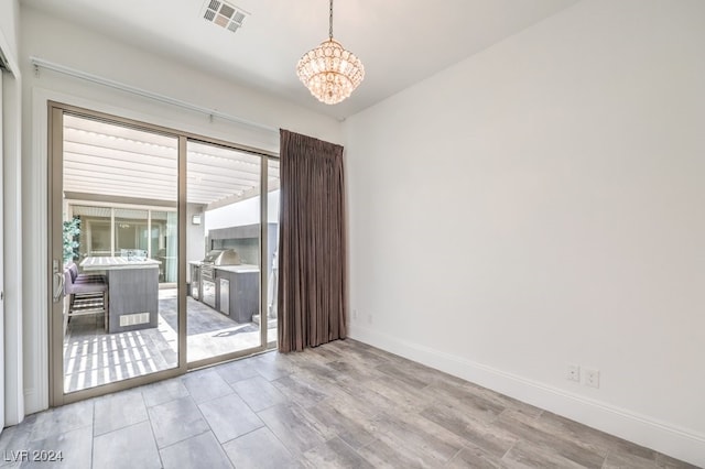 spare room with light hardwood / wood-style flooring and a notable chandelier