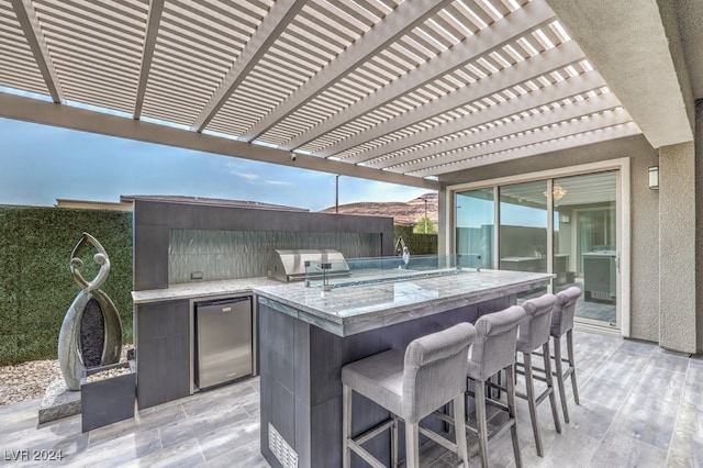 view of patio featuring a pergola, area for grilling, an outdoor bar, and an outdoor kitchen