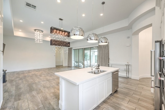 kitchen featuring white cabinets, a center island with sink, light wood-type flooring, and sink